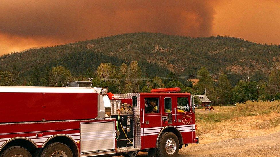 fire truck in oregon on the way to help wildfires. lots of smoke in the background.