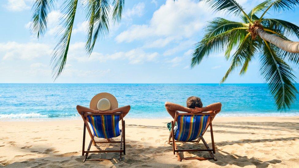 Two people on deck chairs on the beach