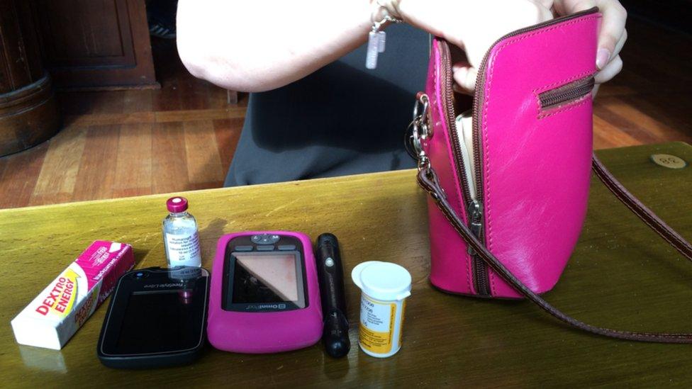 Diabetes medicine and equipment next to a pink handbag