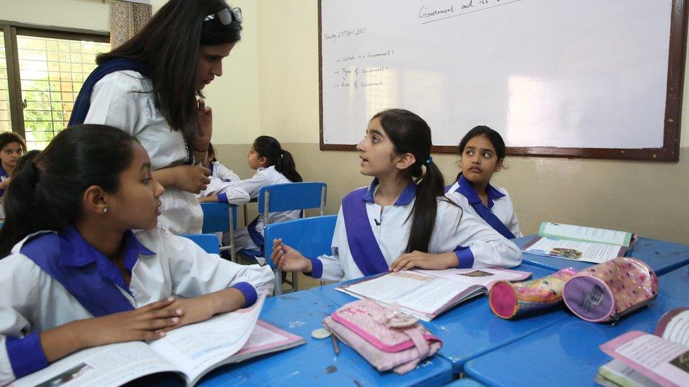 Zymal talking to her teacher at school while sitting with her classmates