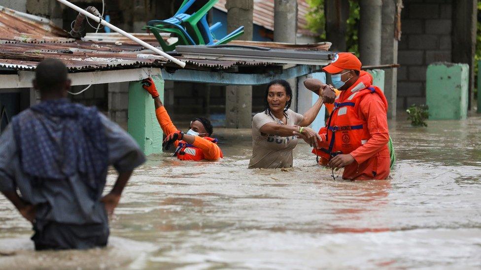 Members of the Civil Defence help a woman in a flooded street after the passage of Storm Laura, in Azua, Dominican Republic August 23, 2020.