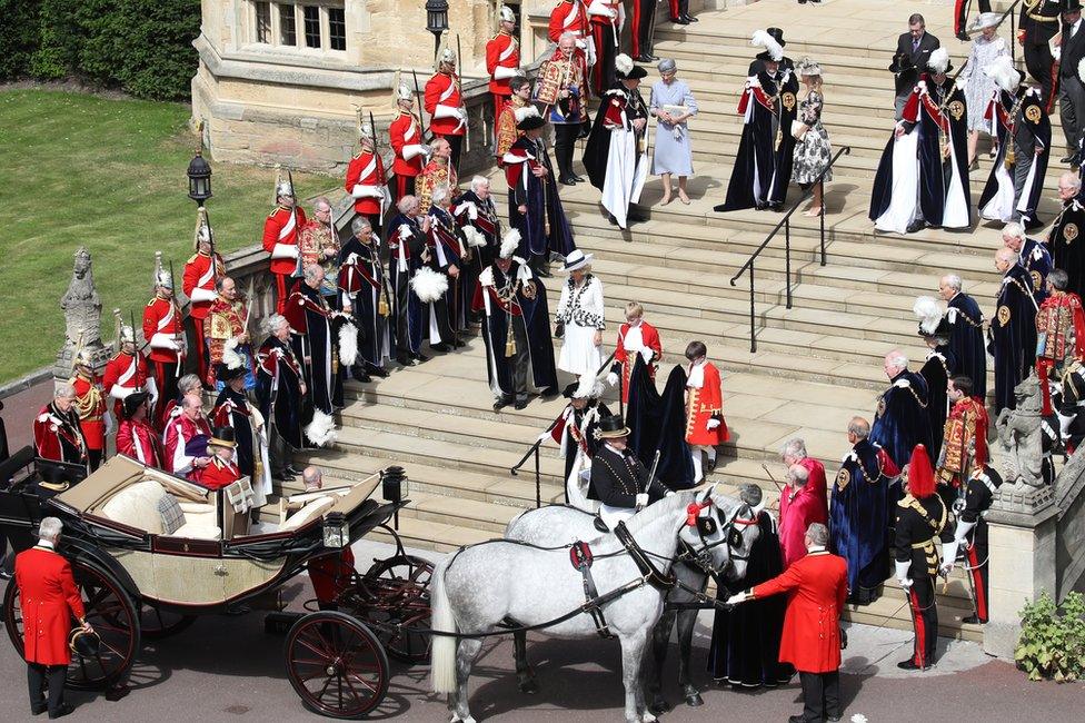 Guards, military, other members of the Royal Family and the Knights of the Garter look on as Queen Elizabeth II walks down the steps to her carriage during the Order of the Garter Service at Windsor Castle