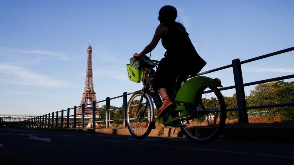 A woman rides a Velib bicycle-sharing service near the Eiffel Tower