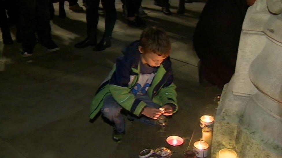 A boy lights at candle at the vigil in Birmingham