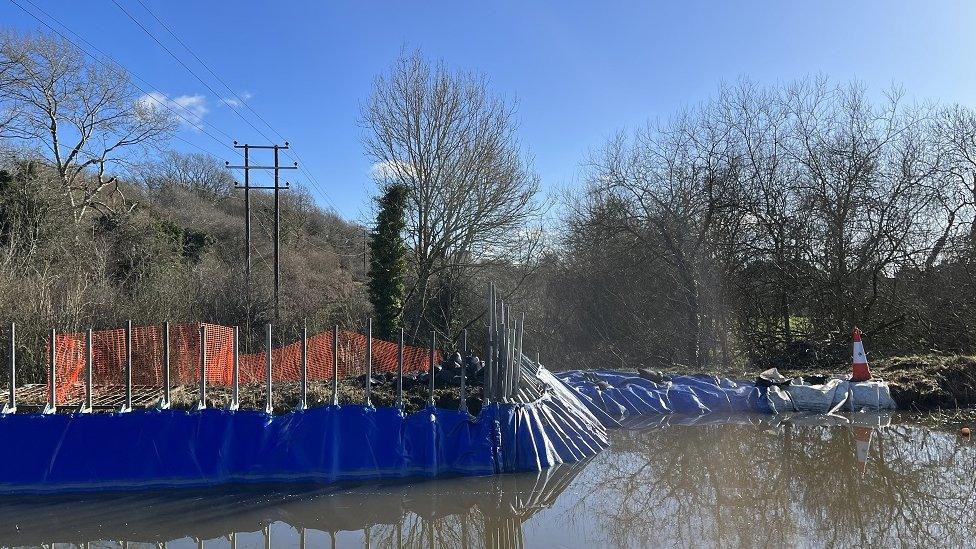 A canal in winter with a section surrounded by tarpaulin