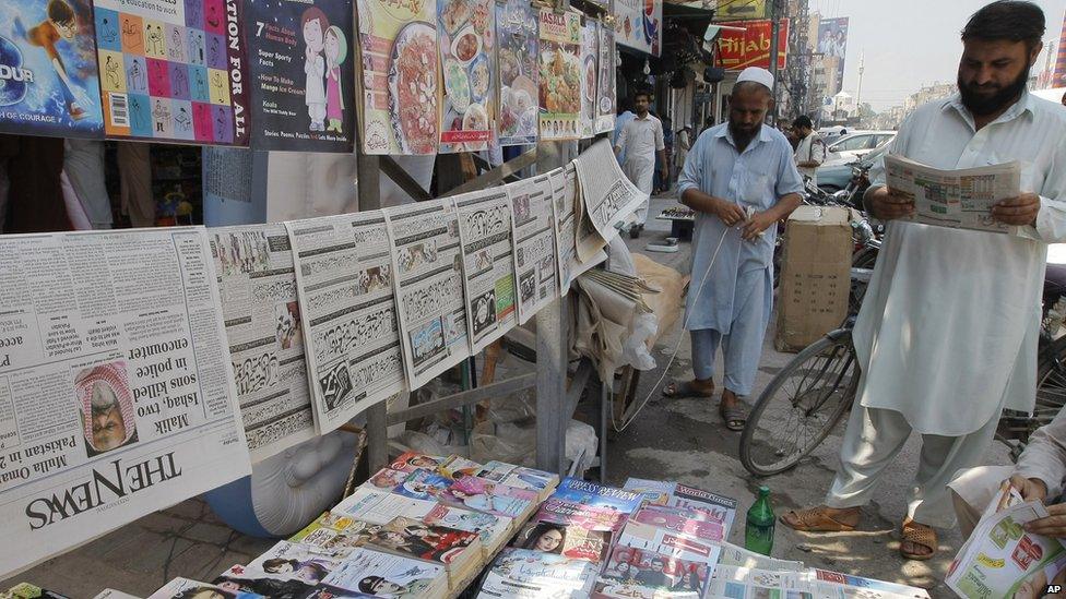 Pakistani men read newspapers at a stand in Peshawar