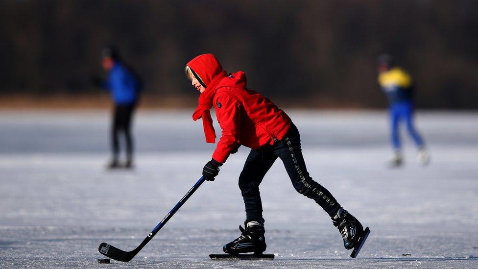 A boy plays ice hockey on the Nannewiid, a lake frozen over as temperatures stay below zero and locals enjoy activities like speed skating, ice hockey, using sleds and walking dogs on February 12, 2021 in Oudehaske, Netherlands.