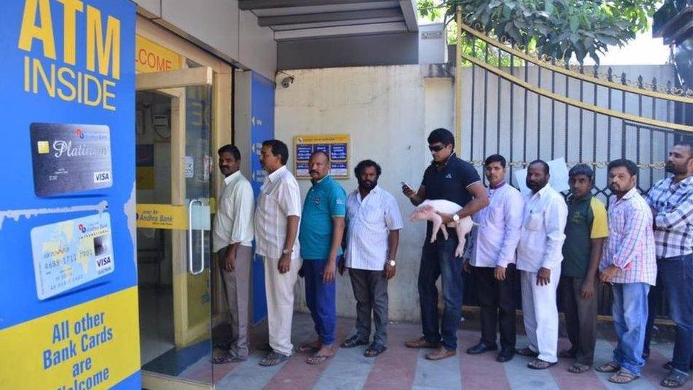 Ravi Babu with the piglet standing in line at the ATM