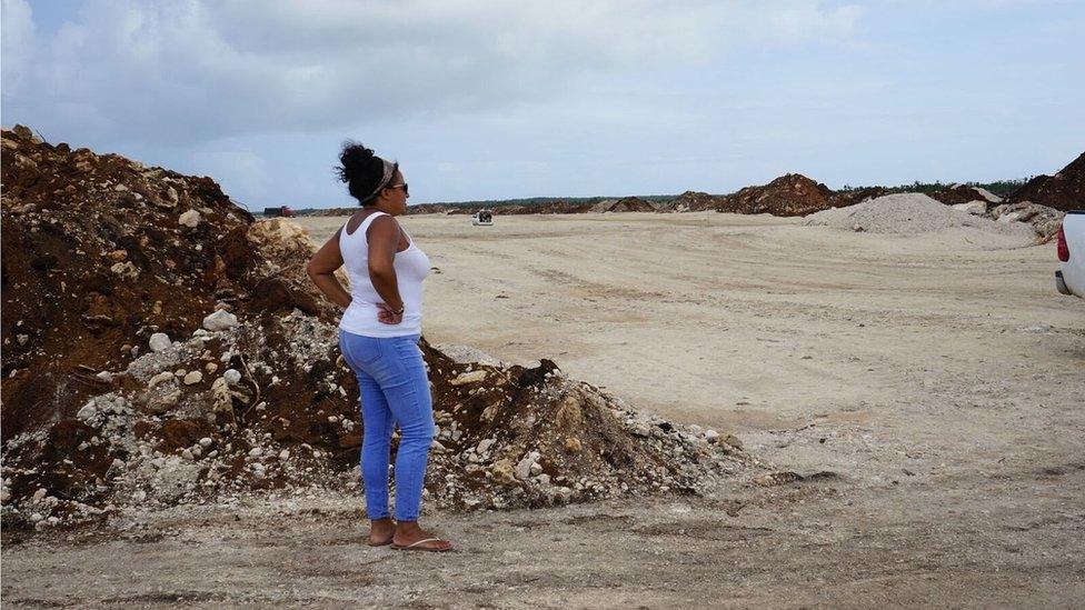 A woman looks on as construction work is under way for a new runway