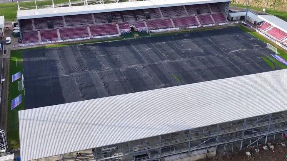 Football stadium from above, showing a partially-completed stand