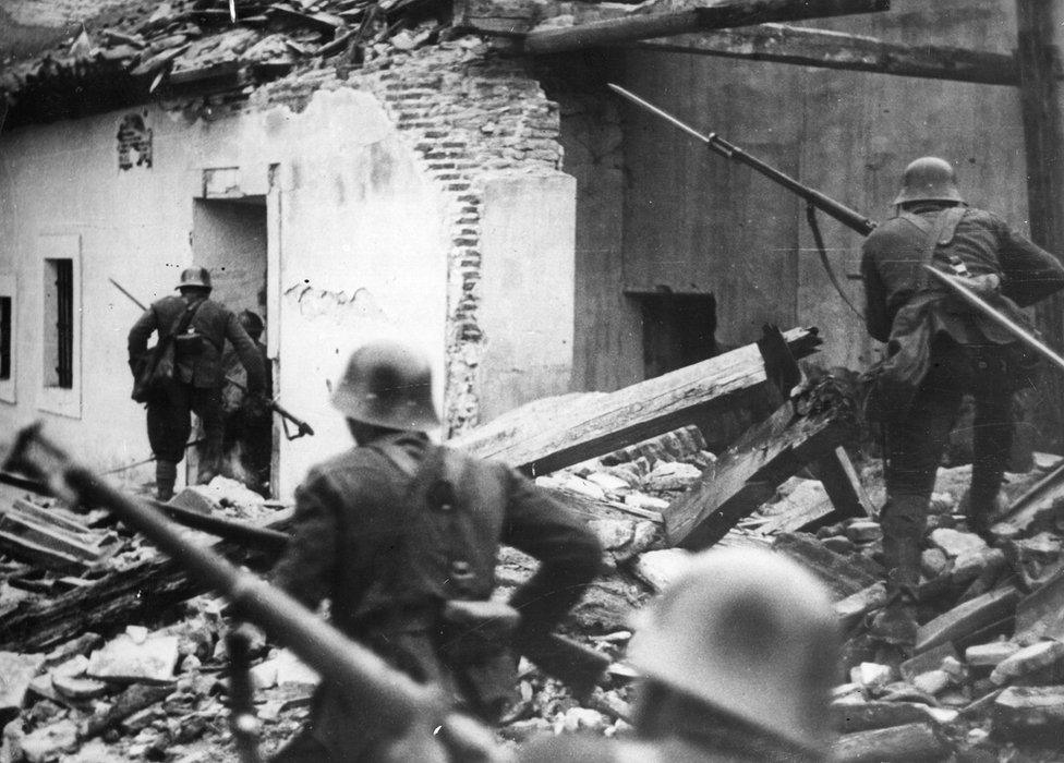 Nationalist troops loyal to General Franco advance, bayonets fixed, through the debris of houses in Madrid wrecked in air raids during the Spanish Civil War