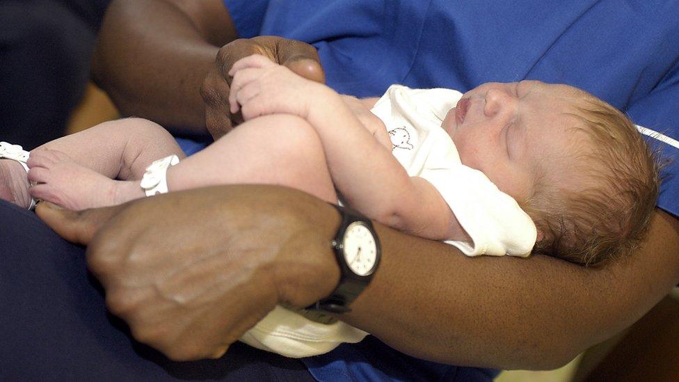 Midwife holds a new born baby