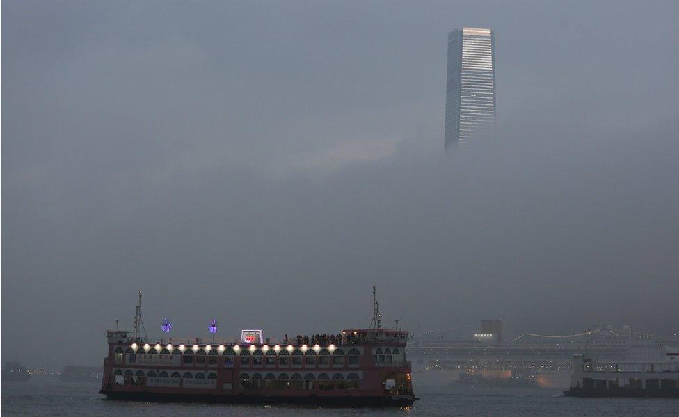 A ferry in Hong Kong harbour, sails in front of the ICC building, in foggy weather on 9 March 2016