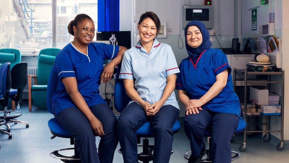 Emma Willis (pictured centre) with two midwives in blue uniforms