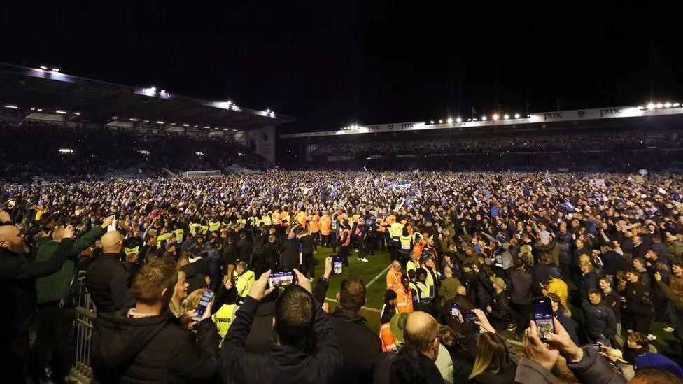 Crowds of fans on the Fratton Park pitch at night after a match