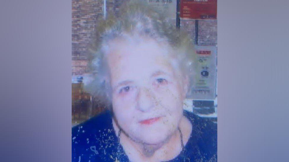 An older lady with grey hair wearing a blue top