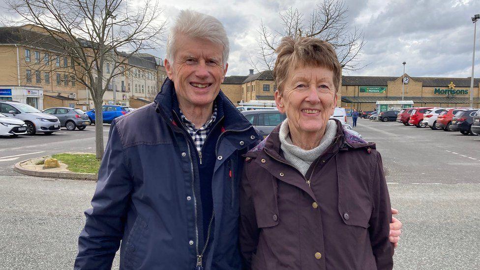 Richard and Jill Hynes standing together - he is wearing a navy jacket and she is wearing a dark burgundy coat