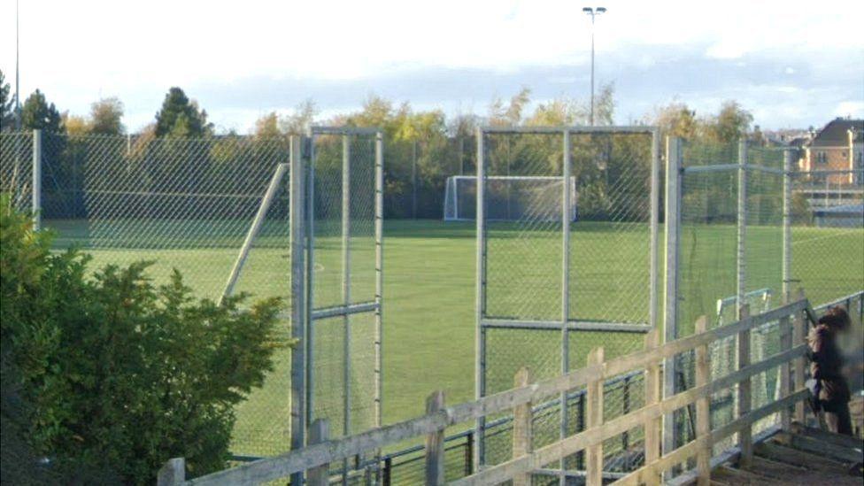 Green AstroTurf with high wire fencing all around it.