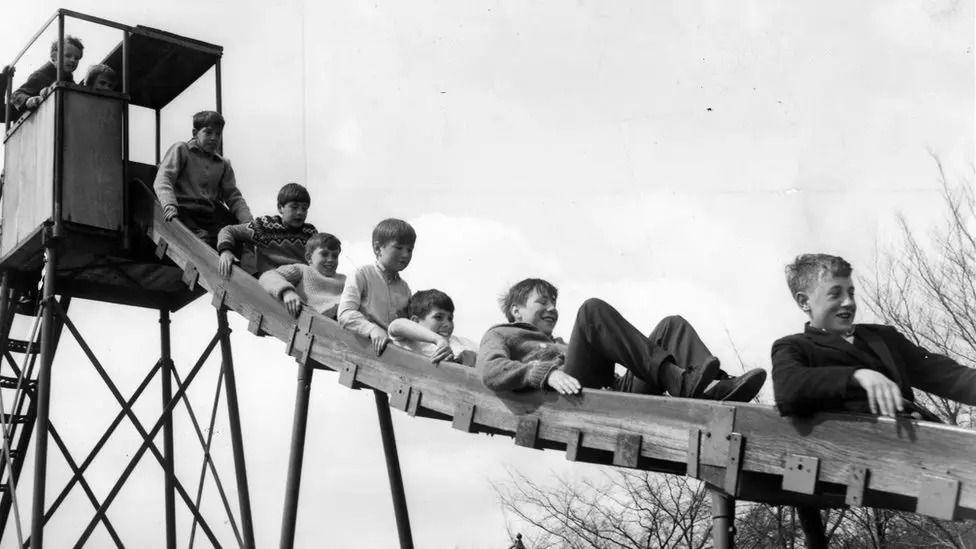 Black and white photo of children on a slide at Wicksteed Park