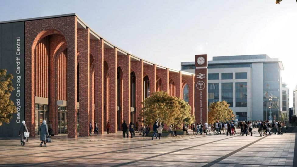 An artist's impression of the back entrance of Cardiff Central railway station, including a tall red brick arch along the back of the building. On the left hand side of the building a grey sign reads: Caerdydd Canolog Cardiff Central. Trees can be seen dotted on the courtyard entrance, and people can see seen walking in crowds outside the building. The British Gas building can be seen in the background.