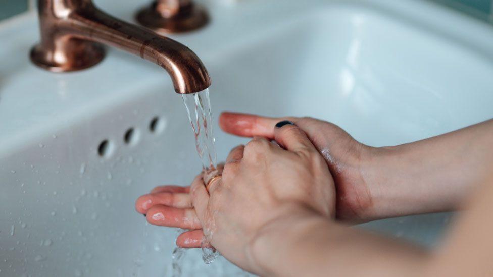 A person washes their hands under a tap