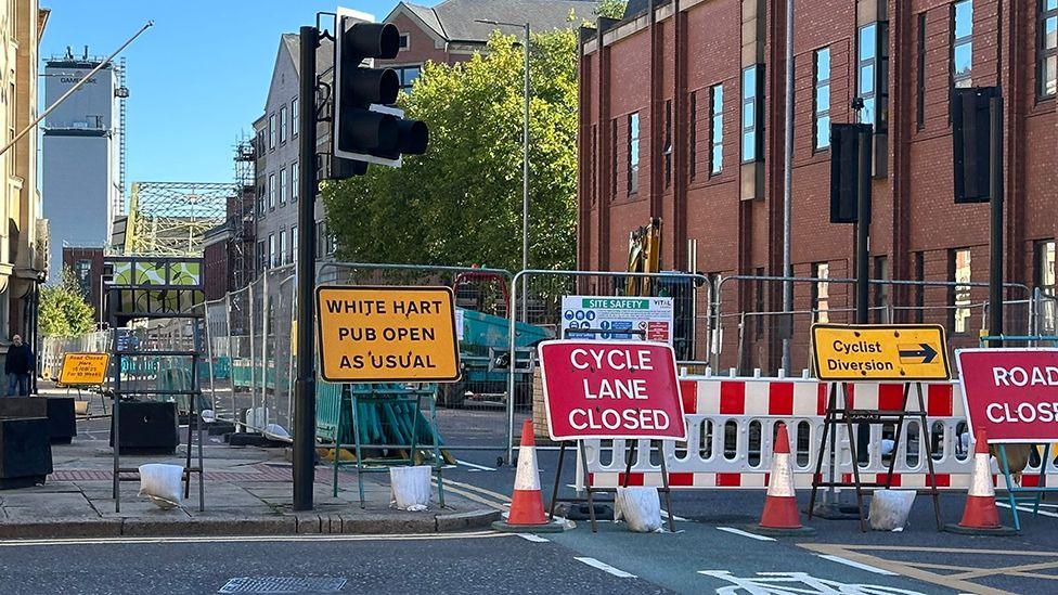 Road closure and diversion signs on Alfred Gelder Street in front of barriers and traffic cones blocking the road.