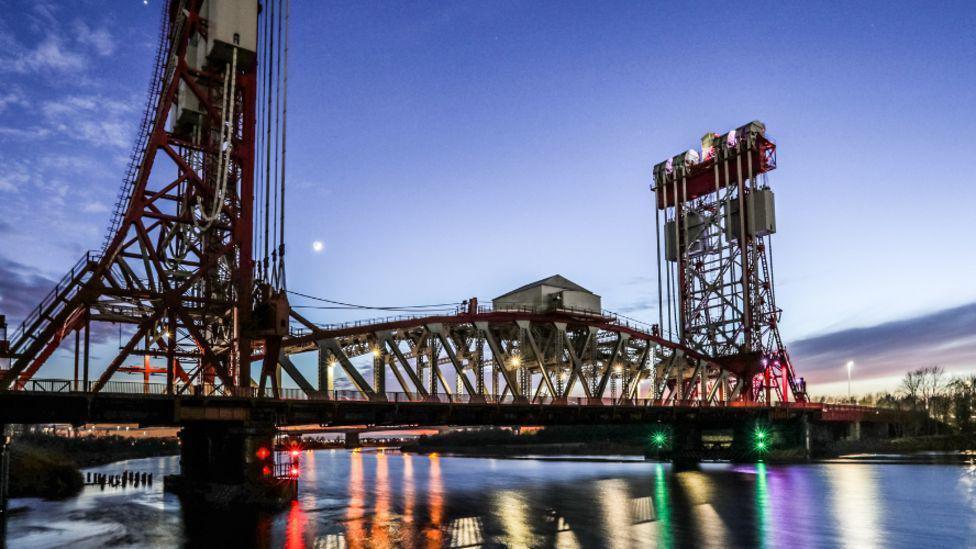 Newport Bridge across the River Tees at sunset, with lights reflecting in the water