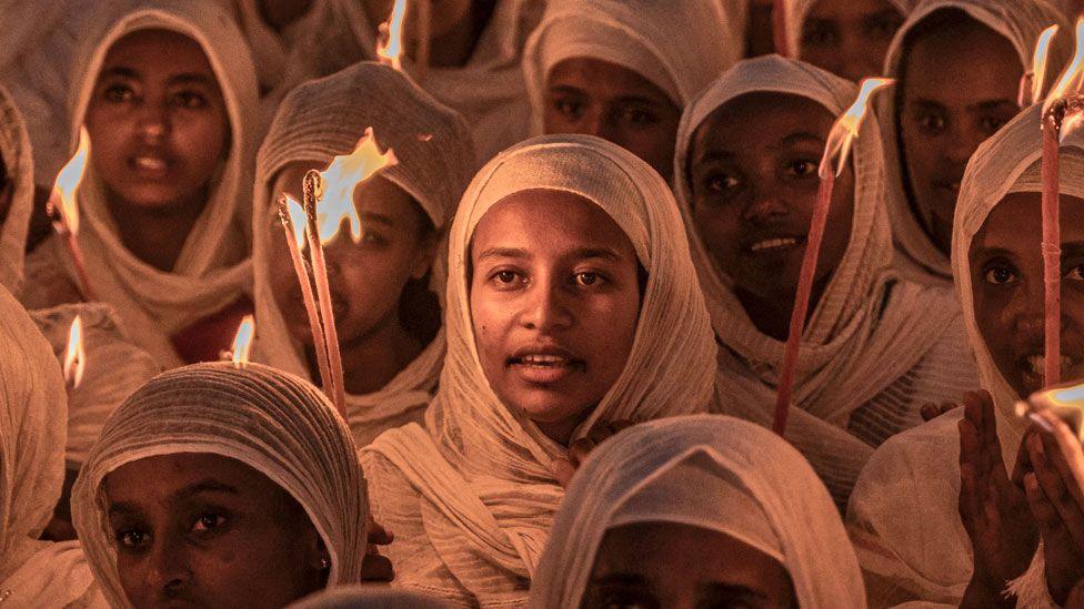 Orthodox Christian women wearing white head scarves and holding candles  at prayers ahead of Christmas celebrations at the Bole Medhanialem Church in Addis Ababa - 6 January 2024