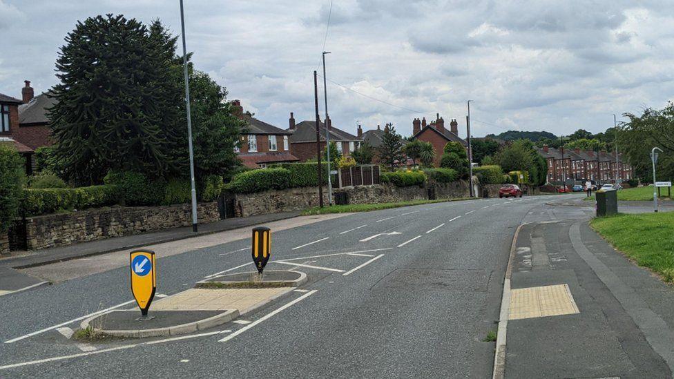 View down wood lane with road in middle and semi-detached red brick homes on either side