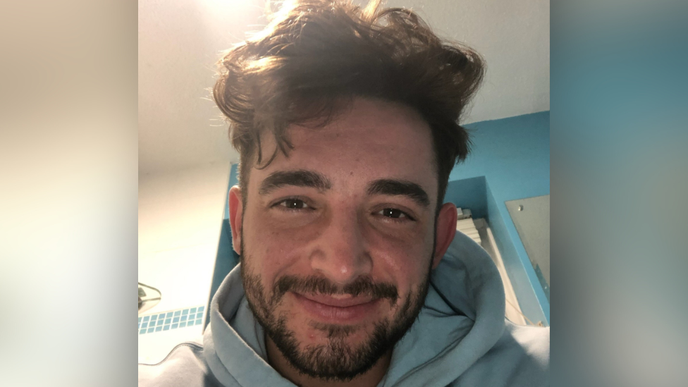 Cain Donald has medium length brown hair and a short brown beard.