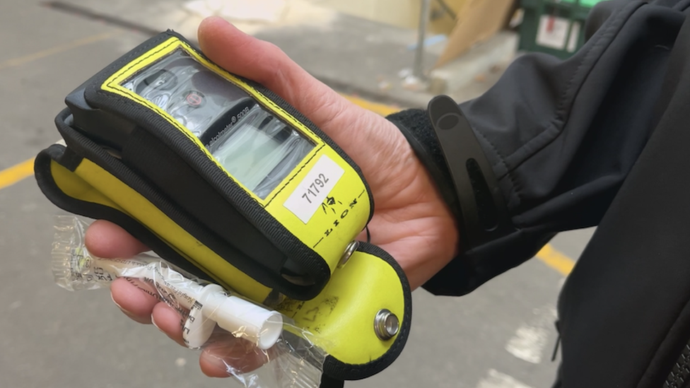 A police officer holding a breath test kit