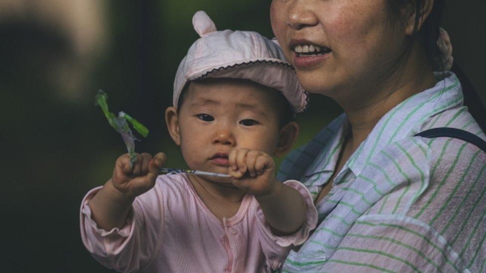 A woman walks with a baby on a street in Shanghai, China, 31 May 2021.