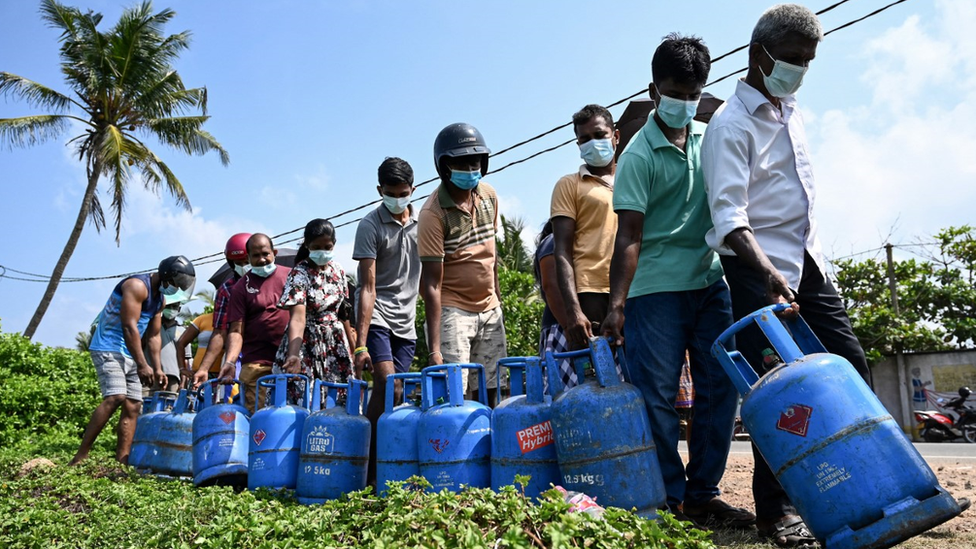 Sri Lankans queue with canisters on a roadside for liquefied petroleum gas, which many households use for cooking.