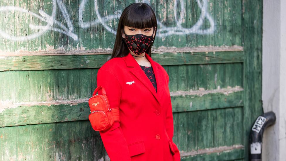 A model poses outside the Marine Serre show wearing a facemask