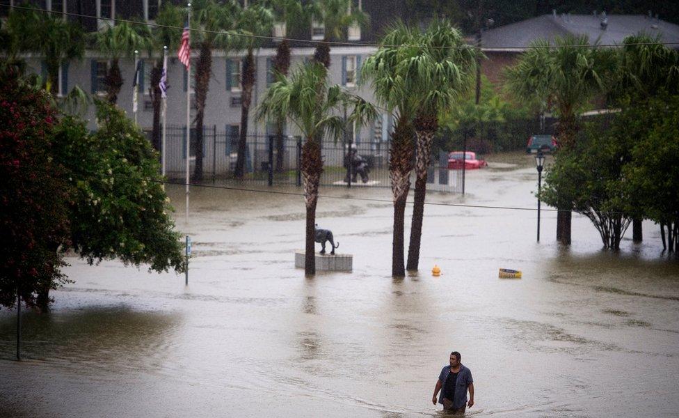 A resident wades through flood water at Tiger Manor Apartments by the North Gates of LSU, Saturday, Aug. 13, 2016, in Baton Rouge, La.