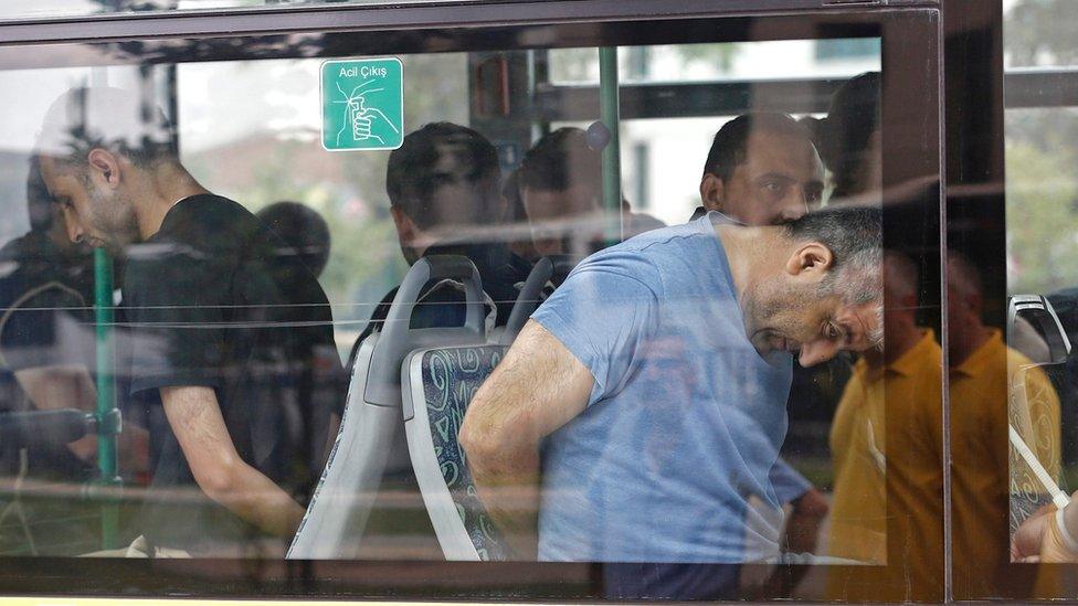 Turkish plain cloth policemen accompany detainee soldiers after the 15 July failed coup attempt at a bus as they arrive to Istanbul court