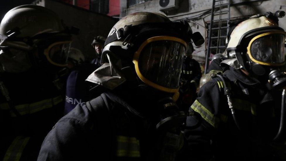 Chinese firemen gather at the site of the house fire