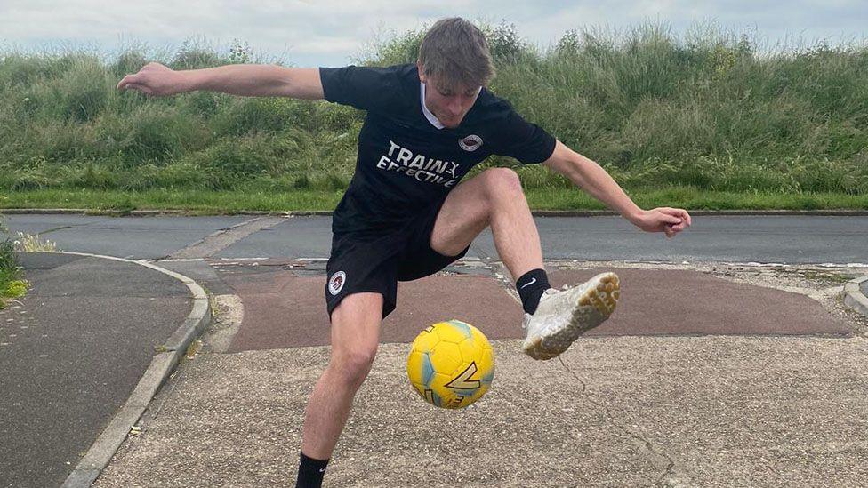 James Pope kicking a yellow ball 