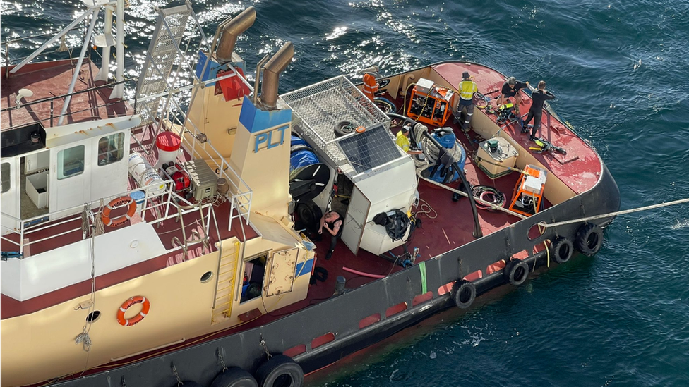 Workers prepare to clean the ship's hull