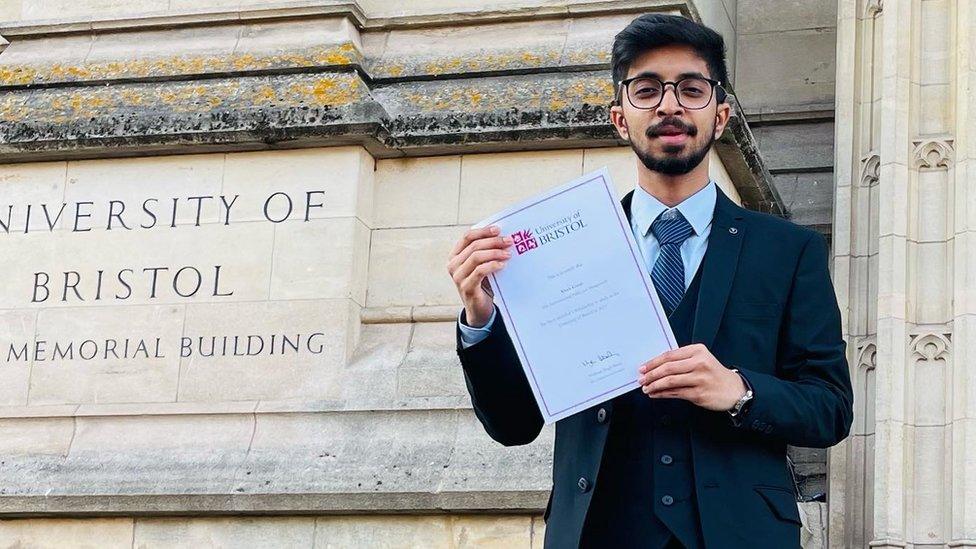 Vivek Gurav standing outside the University of Bristol holding his masters