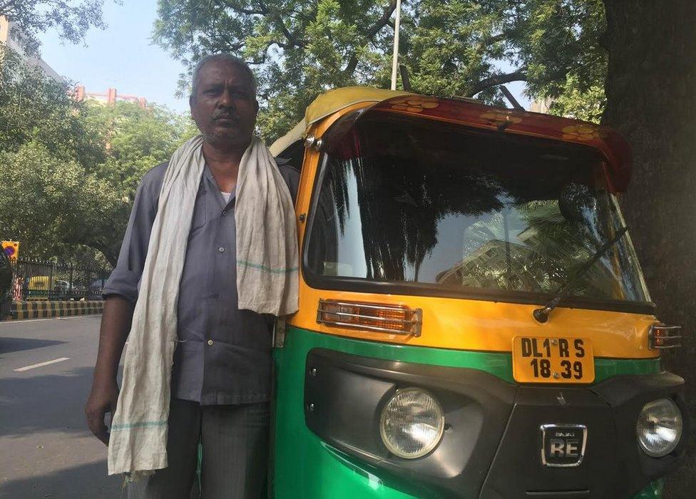 Mahendra Sharma standing next to his tuk tuk