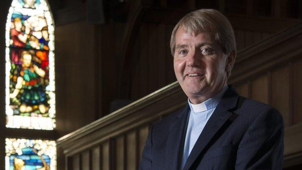 The Reverend Dr Russell Barr, the Church of Scotland's moderator designate standing in front of a stained glass window