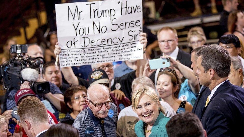 Hillary Clinton in a crowd where one person is holding up a sign that reads "Mr Trump have you no sense of decency Sir", 11 August 2016