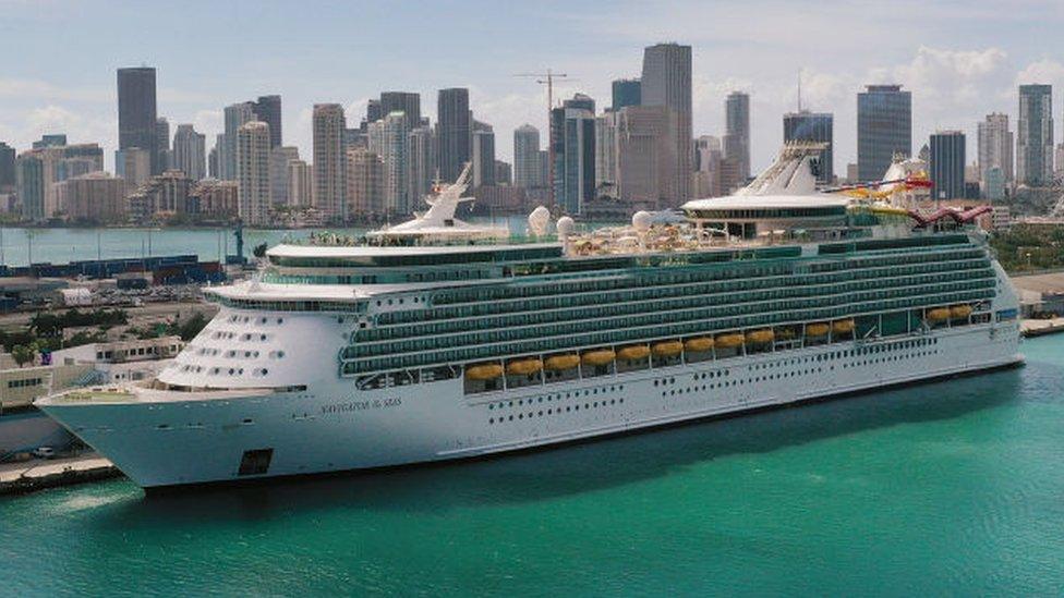 cruise ship docked in Miami with city skyline behind it