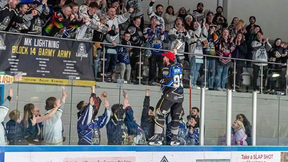 MK Lightning player waving cup towards fans in the stand