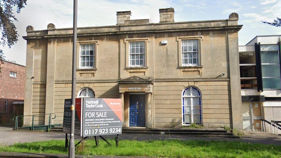 Grand two storey building with five large windows and a blue front door