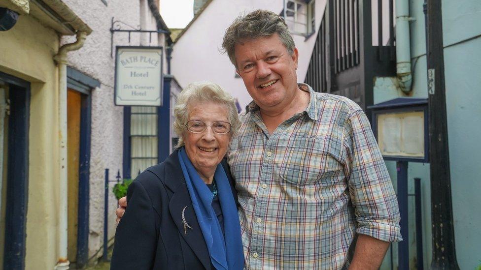 Jo Collie on left with son Michael Collie on right in front of buildings