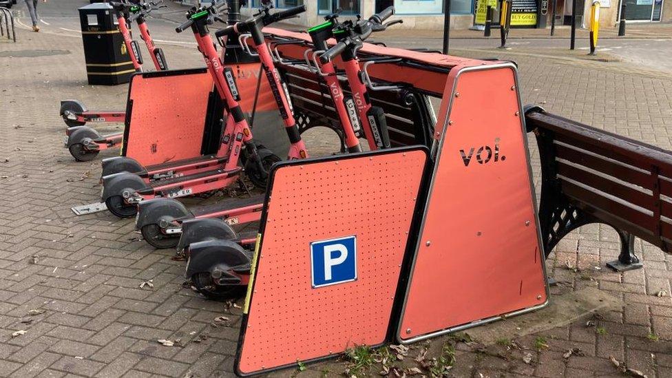 Orange scooters in a rack in the street