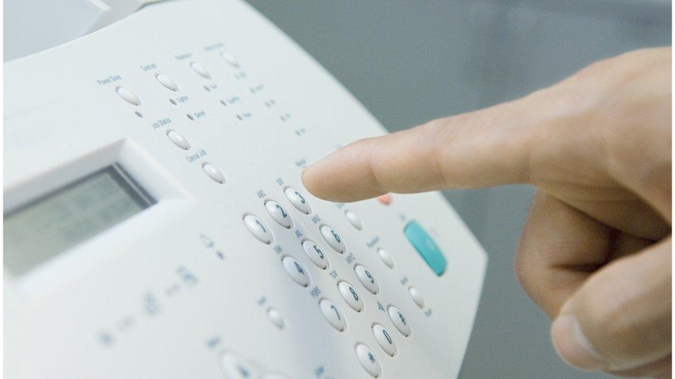 A person pressing a fax machine