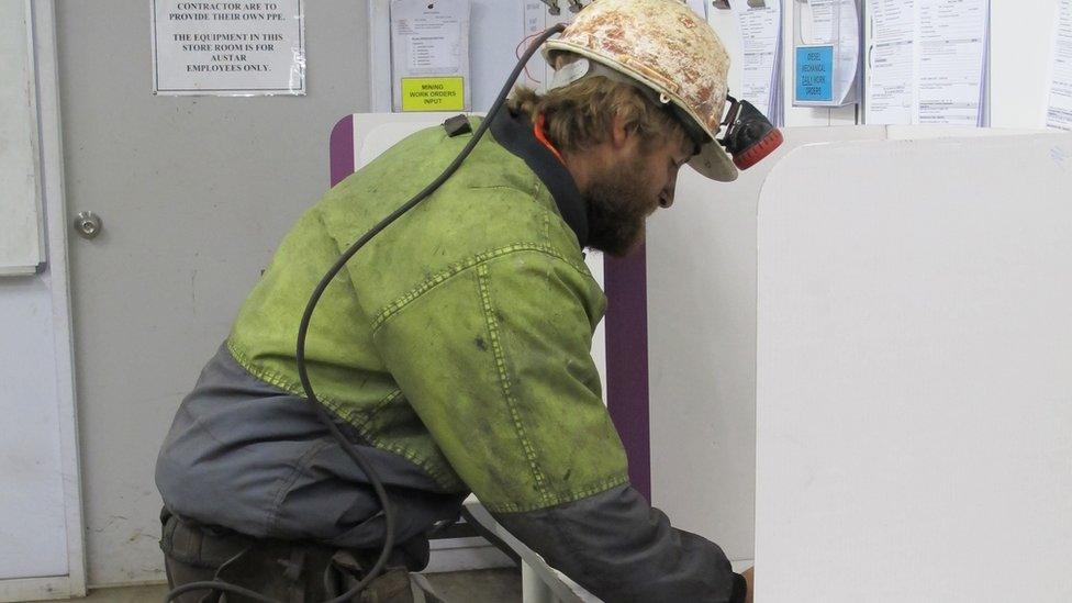 A miner votes in a polling booth